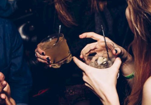 A group of people casually enjoying drinks together, with one person laughing and engaging in conversation, in a lively and social setting.