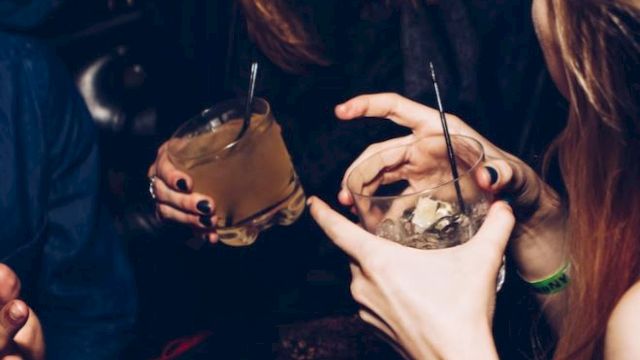 A group of people casually enjoying drinks together, with one person laughing and engaging in conversation, in a lively and social setting.