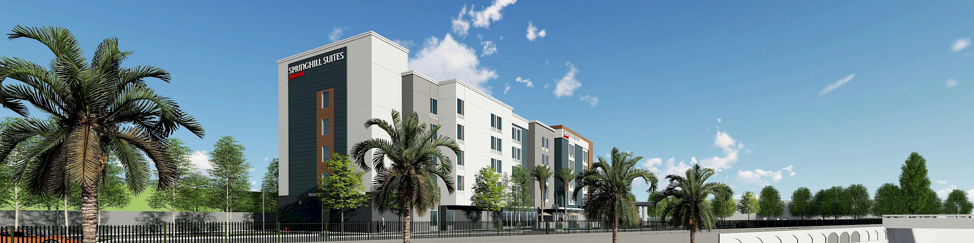 The image shows a modern building with palm trees and cars parked along the street, under a sunny blue sky.