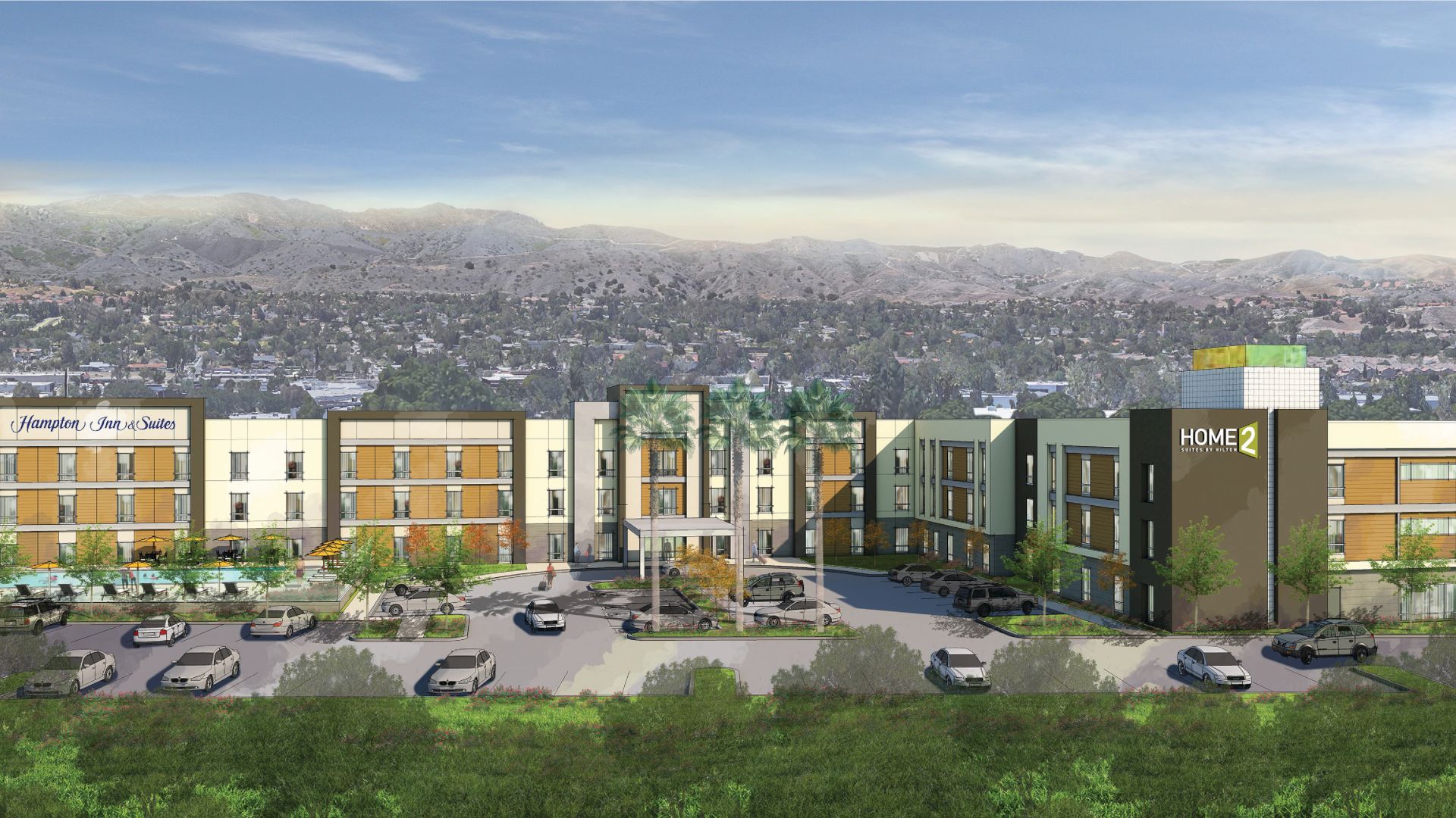 A modern hotel complex with a spacious parking lot sits against a hilly backdrop under a partly cloudy sky.
