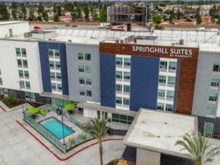 The image shows a SpringHill Suites by Marriott hotel featuring an exterior view with a small outdoor pool and surrounding buildings.