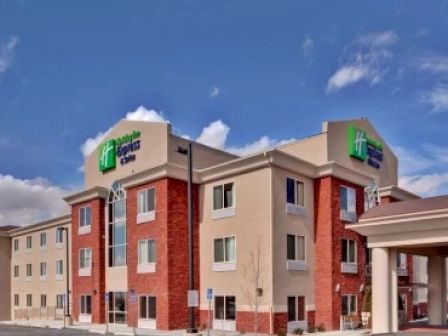 This image shows the exterior of a modern hotel with beige and red brick walls, and a blue sky background.