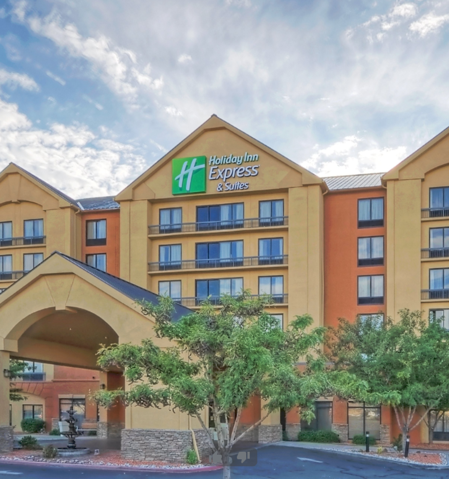 The image shows a Holiday Inn Express & Suites hotel with a prominent entrance, multiple stories, balconies, and a parking area in front.