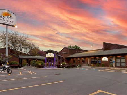 A building with "Sunridge" signage, surrounded by parking spaces and a dramatic sunset sky.
