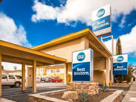 This image shows a Best Western hotel with clear signage, a few parked cars, and a partly cloudy sky.