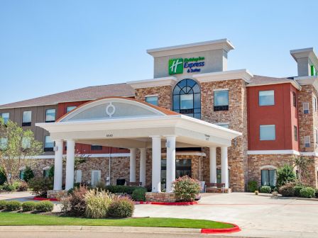 The image shows the exterior of a hotel with a distinct entrance and a sign reading "Holiday Inn Express & Suites."