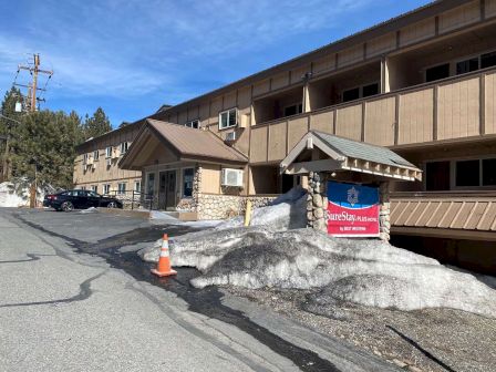 The image shows a building with a banner that reads "Giant Steps" and snow around the entrance, with an orange traffic cone nearby.